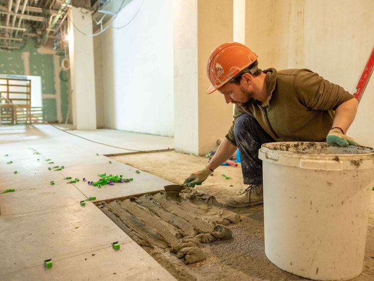 Tiler laying floor tiles on a fit-out project